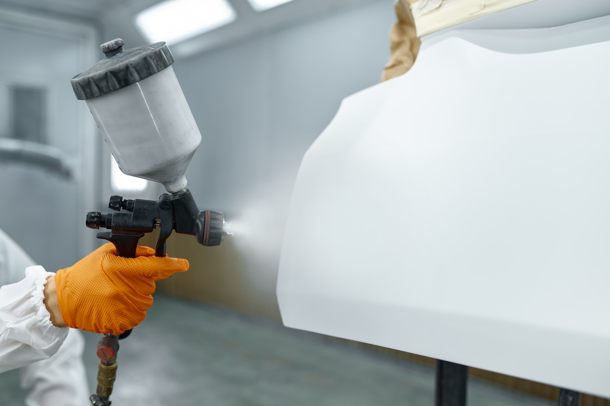 Technician in safety clothing spraying car paint